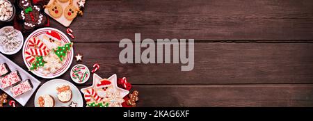 Cute Christmas sweets and cookie corner border. Above view on a rustic dark wood banner background with copy space. Fun holiday baking concept. Stock Photo