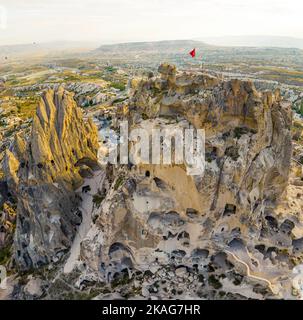 Panoramic drone view of the volcanic tufa rock formations, cave houses carved in stone, Cappadocia, the Central Anatolia Region of Turkey, with the Turkish flag on the highest cliff. High quality photo Stock Photo