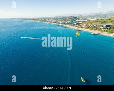 Okurcalar, Alanya, Turkey. Drone view of the wide blue Mediterranean sea with jet skis and boats near the shore, sunny sandy beaches of luxury resorts, mountains in the background. High quality photo Stock Photo