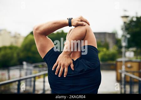 Your goals are so close within reach. Rearview shot of a sporty young man stretching before a run outdoors. Stock Photo