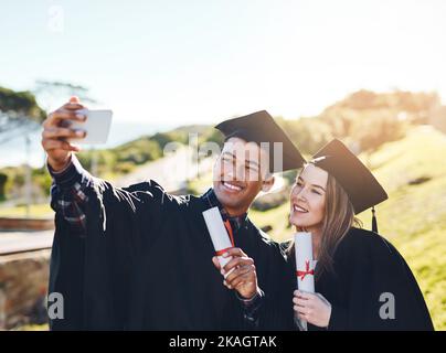 We have a few announcements to make online. two students taking a selfie on graduation day. Stock Photo