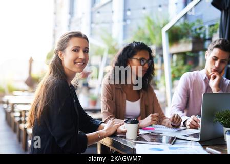 Weve been discussing so many bright ideas. Portrait of a young designer having a meeting with her colleagues at a coffee shop. Stock Photo