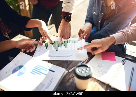 What is the probability of profit. a group of colleagues having discussing paperwork during a meeting at a cafe. Stock Photo