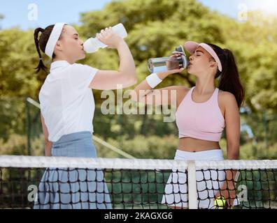 Water, tennis women hydrate and fitness workout with training coach relax on tennis court. Team health, success sports exercise and goal motivation or Stock Photo
