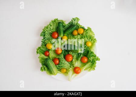 Fresh organic vegetables on a plate on a white table or background Stock Photo