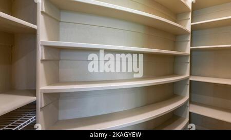 Panorama Kitchen pantry interior of a house with wooden shelving unit. Small spaced empty pantry with wall shelves with curved and edged structures an Stock Photo