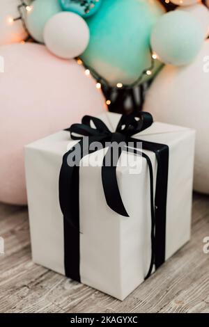 White box with a gift near balloons for the day of gifts Stock Photo