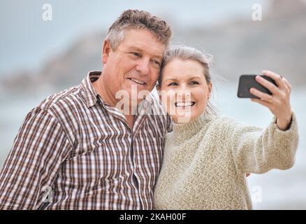 Phone, selfie and beach with a senior couple taking a photograph while on holiday or vacation travel together. Mobile, summer and retirement with a Stock Photo
