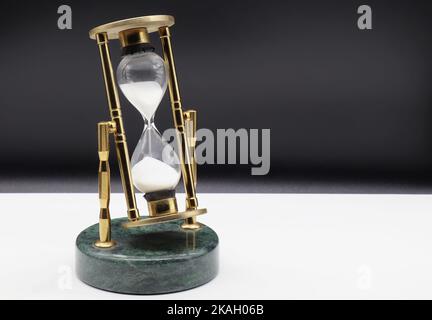 Hourglass on white table isolated on black background. Time passing concept Stock Photo