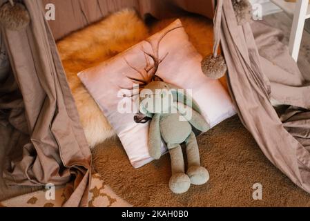 Stuffed bunny toy lies on a pillow on the bed in the children's room Stock Photo