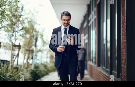 Just stepped away from my desk for a quick coffee. a mature businessman texting on a cellphone while out in the city. Stock Photo