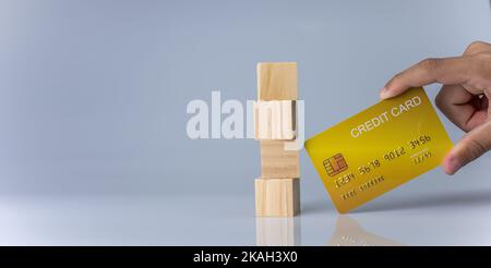 Hands holding credit cards and wooden cube blocks stacked on top of each other. Cashless spending concept. Stock Photo