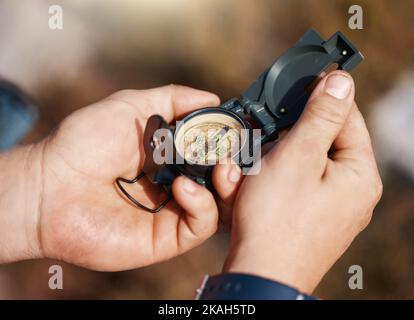 Hands, compass and travel for direction, map or location in adventure, hike or navigation in the outdoors. Hand of traveler holding tracker for scope Stock Photo