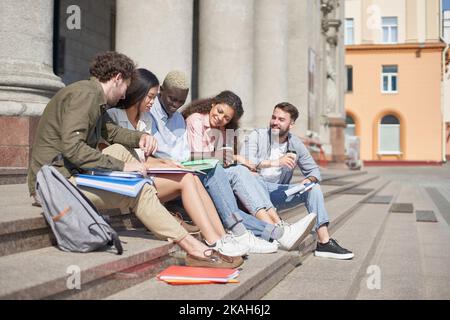 group of students communicates sitting on the steps Stock Photo