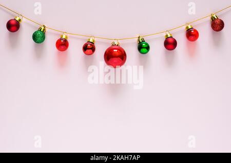 Colorful Christmas baubles ornament hanging on top with pink background. Minimal holiday concept. Stock Photo