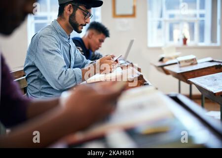 Looking for answers in the right places. university students using smartphones sitting in class. Stock Photo
