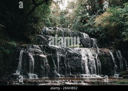 nice small waterfalls in a corner of the mountain hidden with little water falling between the big rocks among the vegetation and trees of the Stock Photo