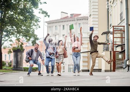 cheerful group of students walking down the street . Stock Photo