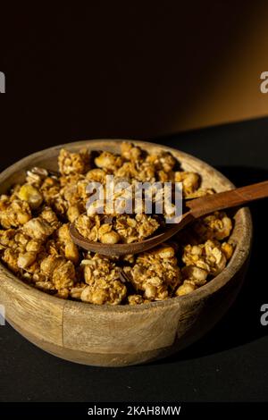 Homemade granola with nuts and seeds in eco tableware wooden bowl. Healthy snack on breakfast. Granola, homemade muesli from oatmeal, raisins, honey, cranberry, flax, almond, macadamia, cashew, freshly baked  Stock Photo