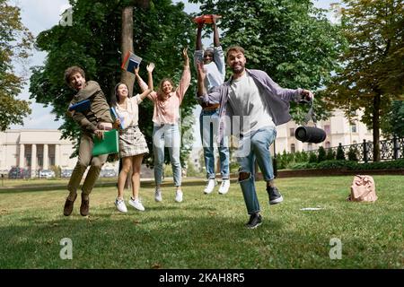 group of cheerful students in standing on the grass in the park. Stock Photo