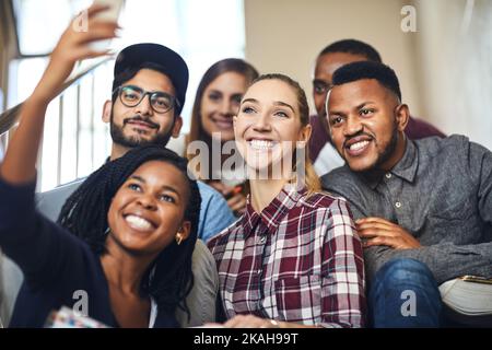 Making memories that will last a lifetime. a group of young university students taking selfies on their campus staircase between classes. Stock Photo