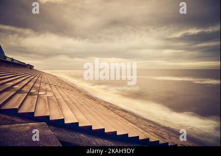 Tide coming in against seawall steps in Blackpool on stormy day in winter Stock Photo