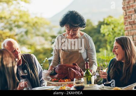 Everyone loves Moms stuffed turkey. a woman bringing a freshly cooked turkey to the dining table. Stock Photo