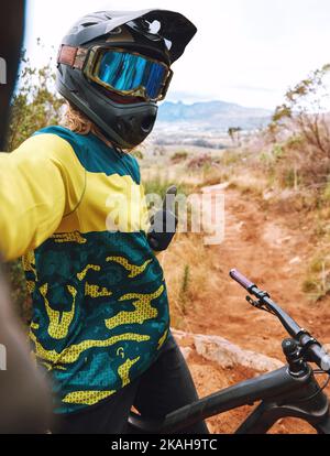 Selfie, cycling and thumbs up by man on bicycle in nature for sport, training and cardio on dirt road. Fitness, influencer and hand thank you sign by Stock Photo