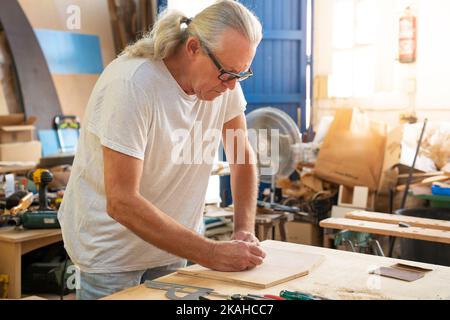 Carpenter working on wood craft at workshop producing wooden furniture. Professional tools for crafting. Work craft concept. Stock Photo
