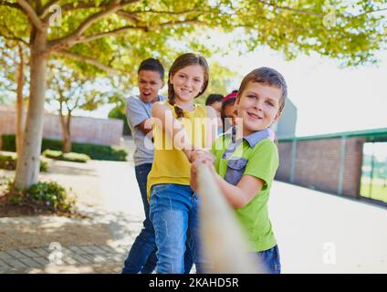 Pull harder, we can do this. a diverse group of children playing tug of war outside. Stock Photo