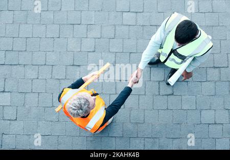 Builder, construction worker and architect handshake with aerial view of teamwork, labor collaboration and industrial project workers. Men shaking Stock Photo