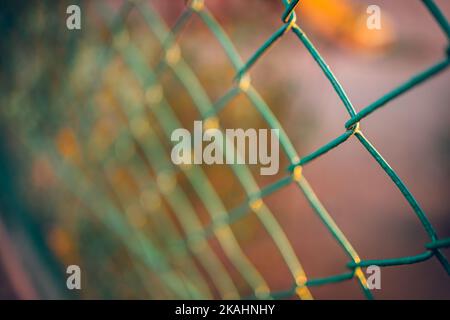 Steel chain link fence, sunset light, artistic dramatic outdoor closeup. Safe, home gourd rail Stock Photo