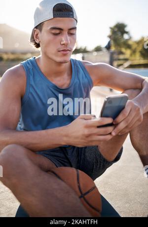 Basketball, sports and man using phone for fitness mobile app, reading online website sport update or internet search for training tips. Healthy teen Stock Photo