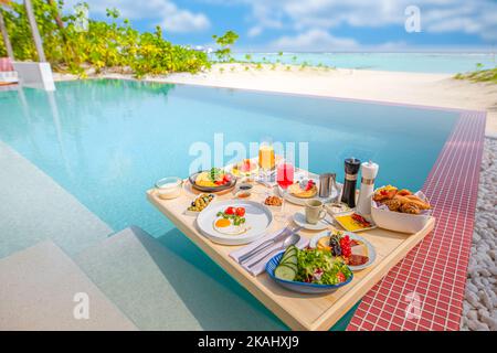 Breakfast in swimming pool, floating breakfast in luxurious tropical resort. Table relaxing on calm pool water, healthy breakfast and fruit plate Stock Photo