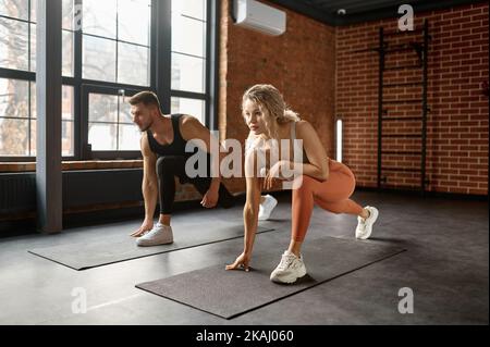 Young couple stretching legs at training gym class Stock Photo