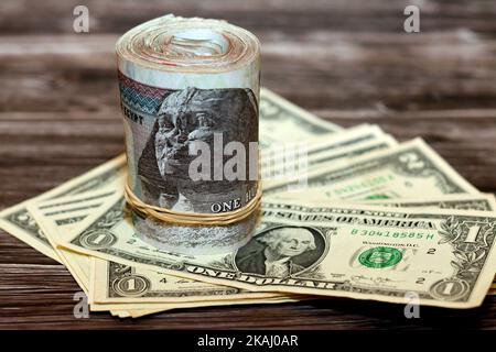 Egyptian money roll of  100 LE and pile of American money isolated on wood, one hundred Egyptian pounds  cash money bills rolled up with rubber bands Stock Photo