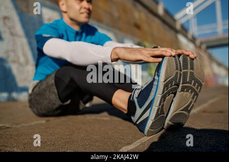 Athletic man doing stretching exercise for leg after of before jogging Stock Photo