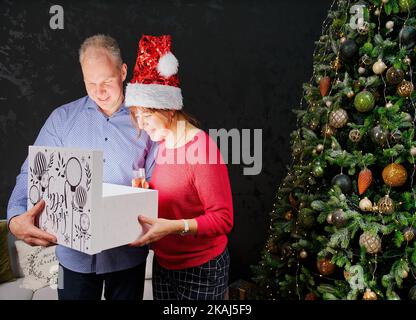 Man giving a Christmas present to his girlfriend. Opening gift box at christmas time. Christmas wonder concept Stock Photo