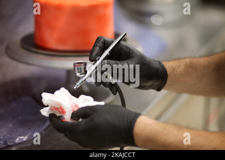 cook preparing a red frosted cake using air bush Stock Photo