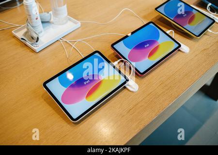 Paris, France - Oct 28, 2022: Pink, blue, silver redesigned iPad by Apple Computers in a row showing advertising image inside Apple Store Stock Photo