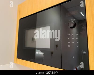 Paris, France - Oct 20, 2022: Side view of modern Bosch microwave oven with black glass and white buttons - reflection of small kitchen Stock Photo