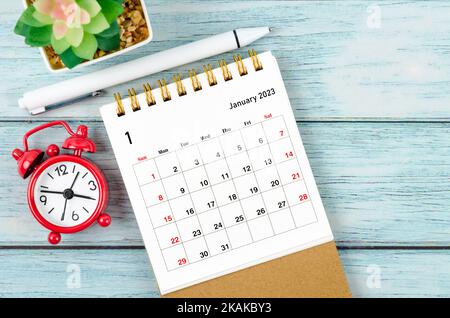 January 2023 Monthly desk calendar for the organizer to plan 2023 year with alarm clock and pen on wooden table. Stock Photo