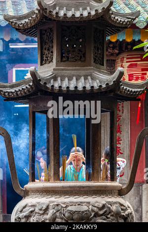 Vietnamese lady offering incense and praying at Jade Empress Pagoda, Ho Chi Minh City, Vietnam Stock Photo