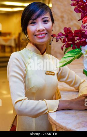 Vietnamese hotel receptionist wearing traditional ao dai uniform, Ho Chi Minh City, Vietnam Stock Photo