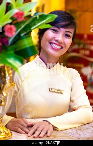 Vietnamese hotel receptionist wearing traditional ao dai uniform, Ho Chi Minh City, Vietnam Stock Photo
