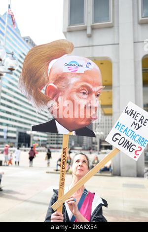 At a Feb. 25, 2017 Affordable Care Act repeal protest rally in Philadelphia, PA, artist Carla Krash holds up a sign with a cartoon image of Donald Trump, that includes a movable hair piece. (Photo by Bastiaan Slabbers/NurPhoto) *** Please Use Credit from Credit Field *** Stock Photo