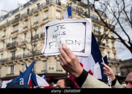 A supporter holds a placard reading 'I am Fillon' stuck under a French national flag during a rally in support of French presidential election candidate for the right-wing Les Republicains (LR) party Francois Fillon at the place du Trocadero, in Paris, on March 5, 2017. The former prime minister hopes to keep his election hopes alive with a rally in Paris but he is struggling to regain the initiative after a week in which members of his team deserted him. Their departures followed Fillon's disclosure that he would face charges over claims he gave his British-born wife and two of their children Stock Photo