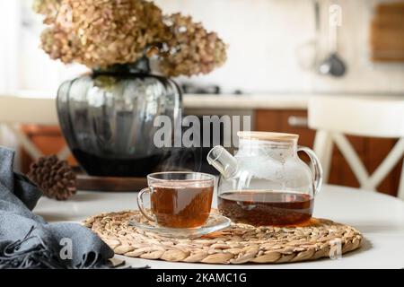 Cup of tea and glass teapot in modern kitchen. Still life in home interior. Close up. Tea time, cozy atmosphere. Stock Photo