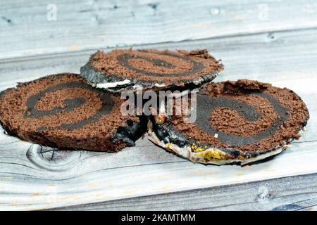 A chocolate cake roll Swiss roll, combination of light chocolate sponge cake with sweet vanilla whipped cream and chocolate ganache dessert, covered w Stock Photo