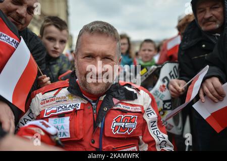 Rafal Sonik, a Polish quad rally driver, signes authographes on Krakow's Main Square during Poland's Flag Day celebration. Flag Day was introduced to Poland in 2004, bridging the gap between International Workers' Day on 1st May and Constitution Day on 3rd May. Today, hundreds of different events were organise across the country, one of them, the 'White and Red relay RMF FM'. At 6 am, the relay carrying the Polish flag left Hel, in the North of Poland, with the flag arriving by boat in Sopot, and then from Gdansk to Warsaw by plane. In the capital, the main point of the program, was a relay o Stock Photo